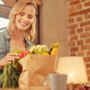 woman with hypothyroidism smiling in front of a grocery bag of nutritious food